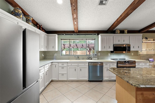 kitchen with beam ceiling, stone countertops, white cabinets, and stainless steel appliances