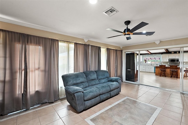 tiled living room with crown molding and ceiling fan