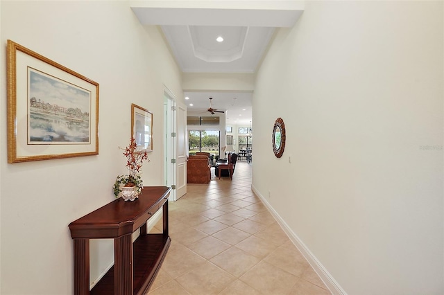 hall featuring light tile patterned floors and a tray ceiling