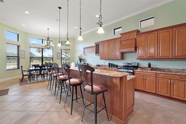 kitchen featuring a kitchen island, a notable chandelier, hanging light fixtures, and stainless steel gas range oven