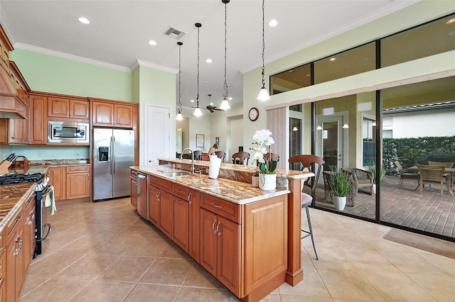 kitchen featuring pendant lighting, ornamental molding, stainless steel appliances, an island with sink, and sink