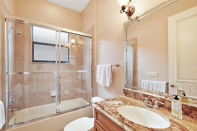 full bathroom featuring toilet, combined bath / shower with glass door, and vanity