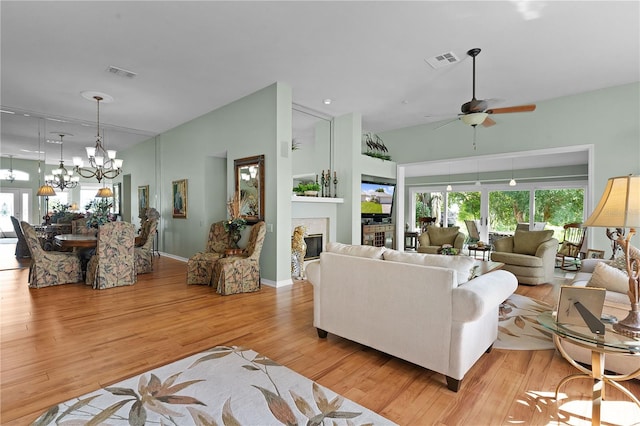 living room featuring light wood-type flooring and ceiling fan with notable chandelier