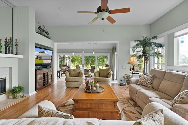 living room featuring a premium fireplace, ceiling fan, and light hardwood / wood-style flooring