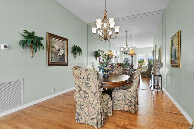 dining space with light wood-type flooring and a notable chandelier