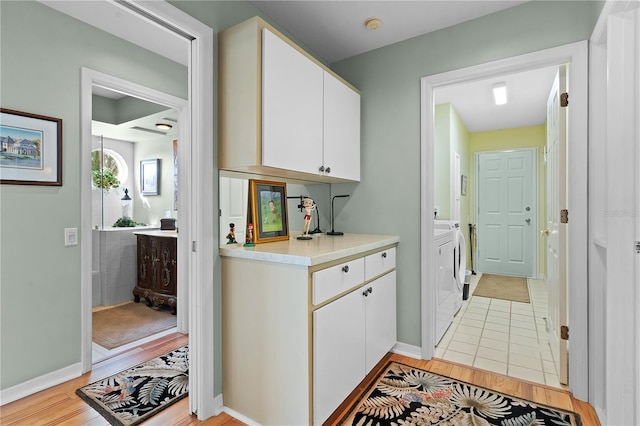 interior space with washing machine and clothes dryer, cabinets, and light wood-type flooring