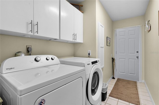 clothes washing area featuring washer and dryer, cabinets, and light tile patterned floors