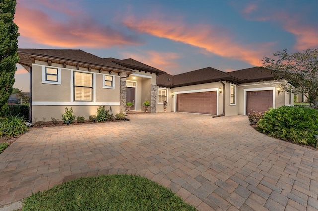 prairie-style house featuring stucco siding, driveway, and an attached garage