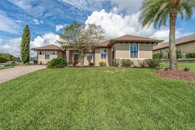 view of front of house with stucco siding, driveway, and a front yard