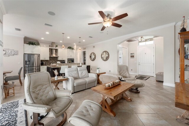 tiled living room with ceiling fan and ornamental molding