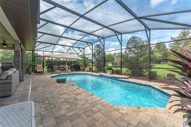 view of swimming pool with glass enclosure, ceiling fan, and a patio