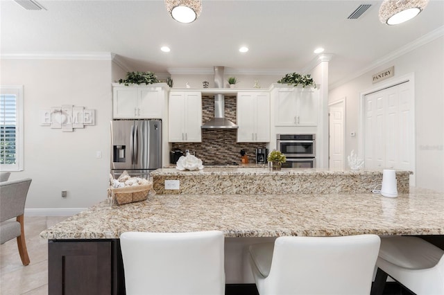 kitchen featuring ornamental molding, white cabinetry, tasteful backsplash, stainless steel appliances, and wall chimney range hood