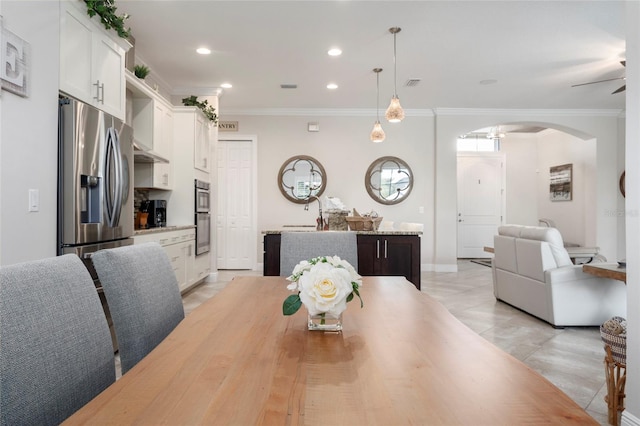 tiled dining area featuring ceiling fan and ornamental molding