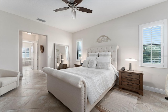 tiled bedroom with ceiling fan, ensuite bathroom, and multiple windows