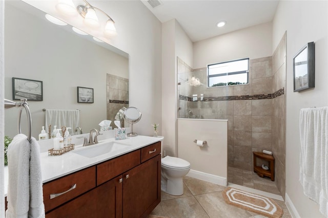 bathroom featuring tile patterned floors, toilet, a tile shower, and vanity