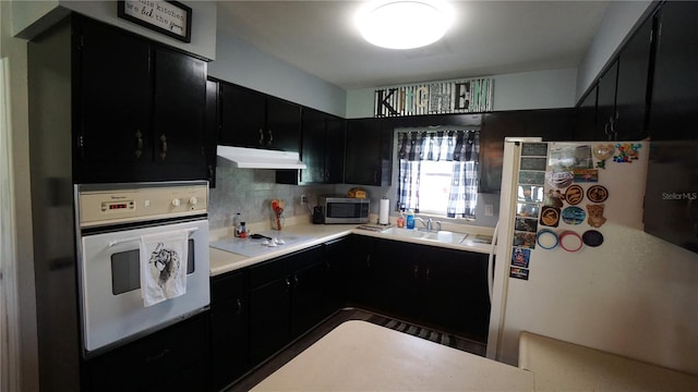 kitchen featuring sink, white appliances, and tasteful backsplash