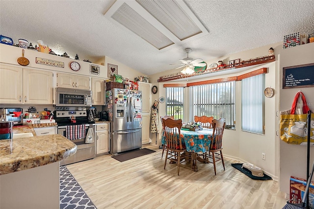 kitchen with stainless steel appliances, vaulted ceiling, ceiling fan, and light hardwood / wood-style floors