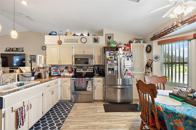 kitchen featuring appliances with stainless steel finishes, lofted ceiling, light hardwood / wood-style flooring, ceiling fan, and decorative light fixtures