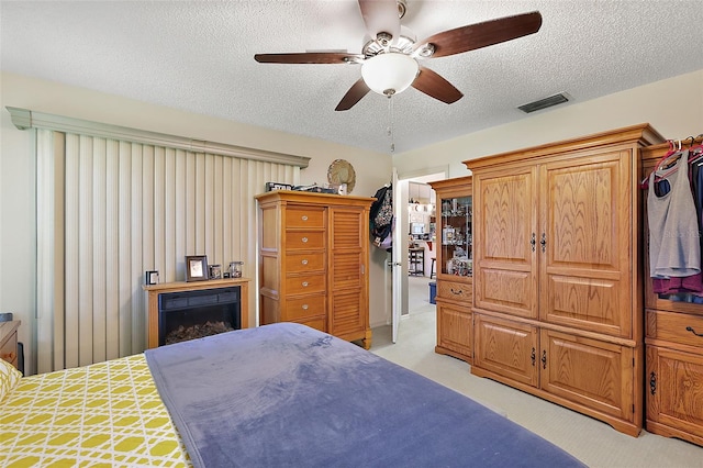 bedroom featuring a textured ceiling, light carpet, and ceiling fan