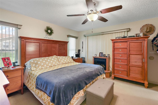 carpeted bedroom with ceiling fan and a textured ceiling