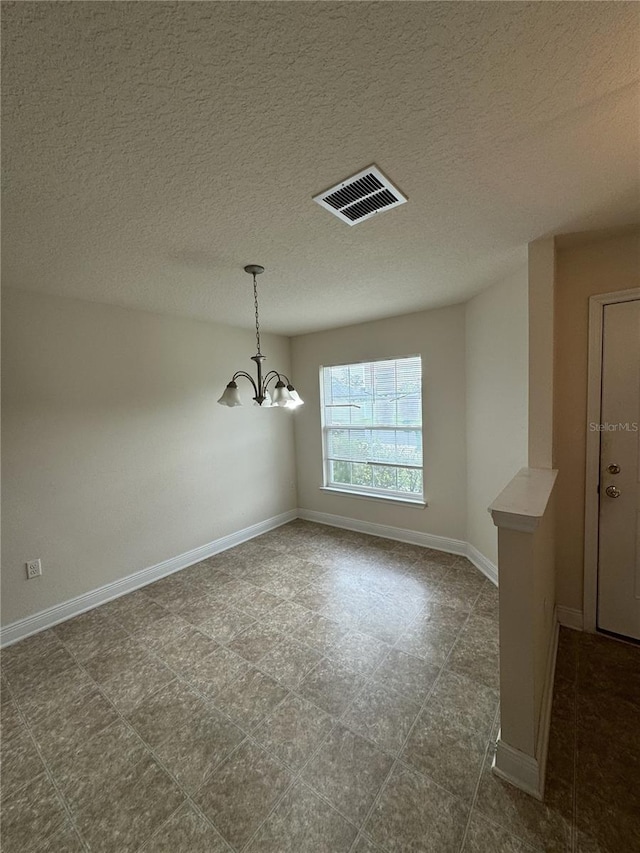 unfurnished room with a textured ceiling and an inviting chandelier