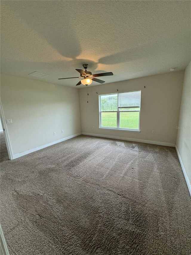 carpeted spare room with ceiling fan and a textured ceiling