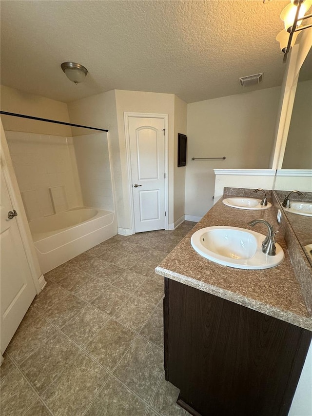 bathroom featuring vanity, a textured ceiling, and bathtub / shower combination