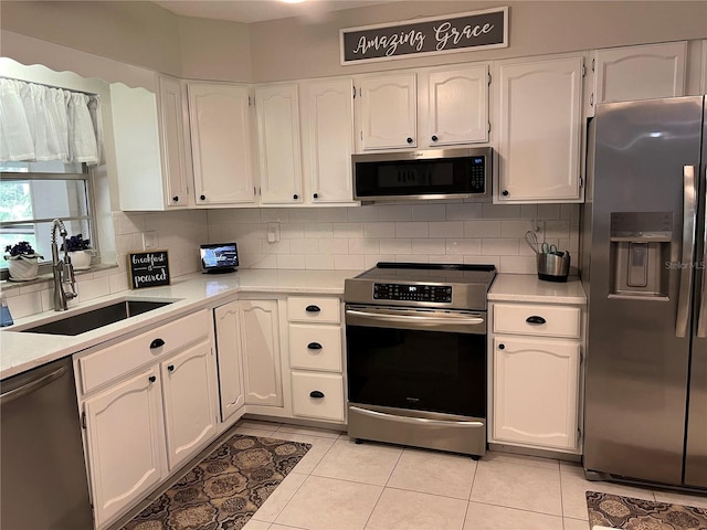 kitchen with white cabinetry, sink, light tile patterned floors, and stainless steel appliances