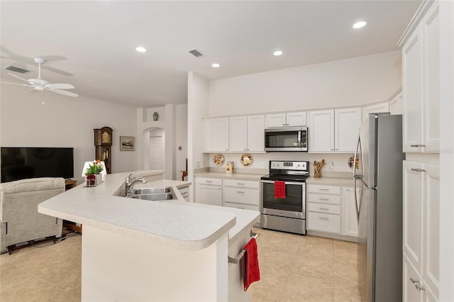 kitchen featuring ceiling fan, stainless steel appliances, white cabinets, sink, and a breakfast bar area