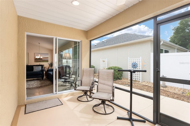 sunroom / solarium featuring an inviting chandelier, wood ceiling, vaulted ceiling, and a healthy amount of sunlight