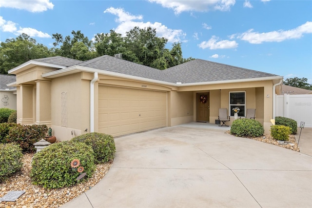 view of front of home featuring fence, driveway, a shingled roof, stucco siding, and a garage