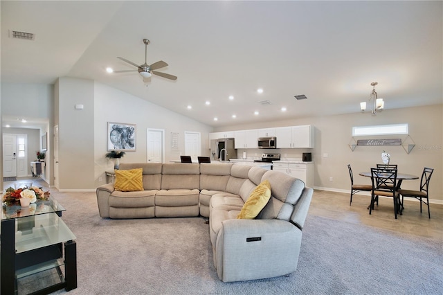 carpeted living room featuring ceiling fan with notable chandelier and high vaulted ceiling