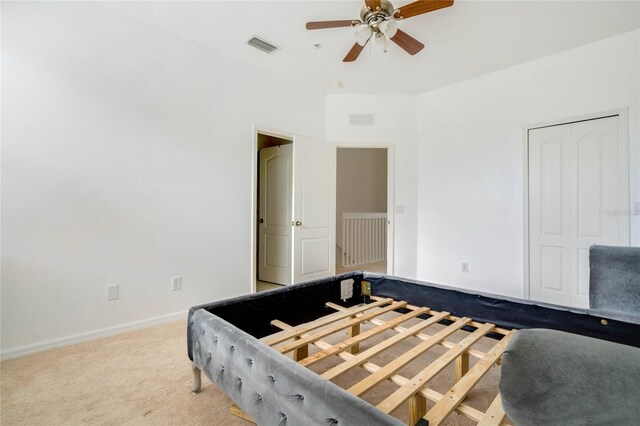 bedroom featuring light carpet, ceiling fan, and a closet