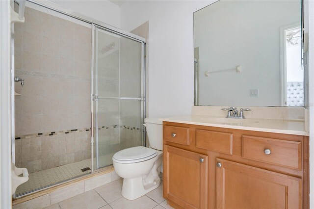 bathroom featuring tile patterned flooring, vanity, toilet, and walk in shower