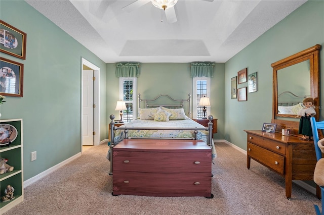 bedroom featuring a tray ceiling, light colored carpet, and ceiling fan