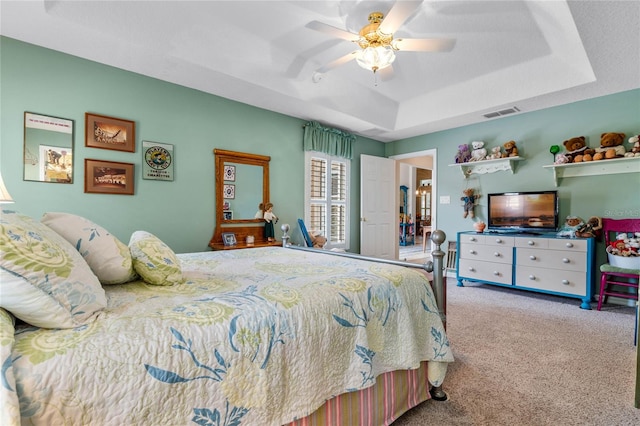 carpeted bedroom featuring a raised ceiling and ceiling fan