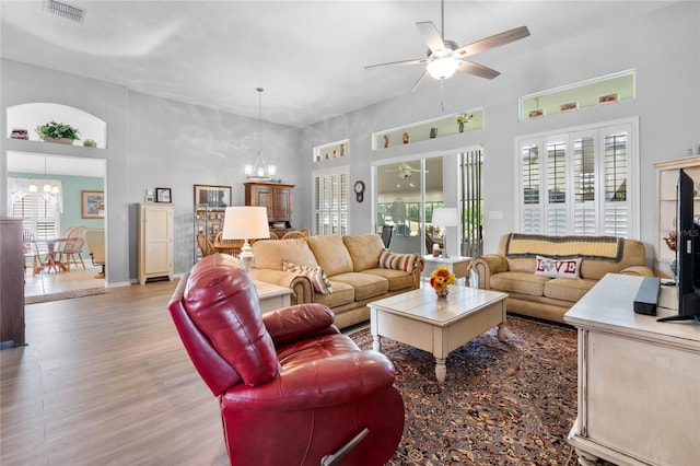 living room featuring ceiling fan with notable chandelier and hardwood / wood-style flooring