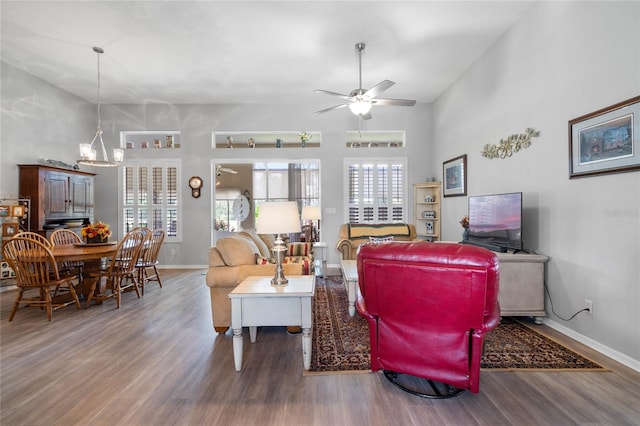 living room with ceiling fan with notable chandelier and wood-type flooring