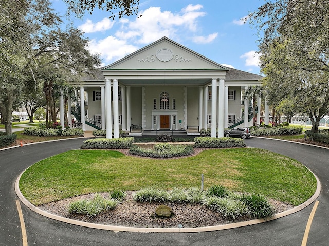 greek revival inspired property with a front lawn and covered porch