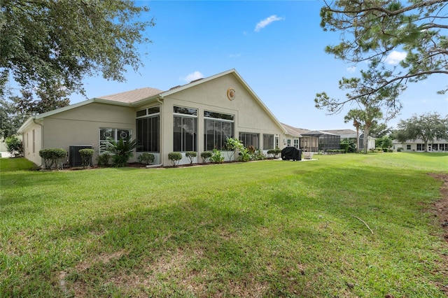 back of house with a sunroom, a lawn, and central AC