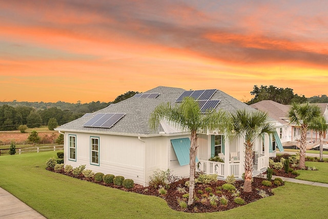 property exterior at dusk featuring a yard and solar panels