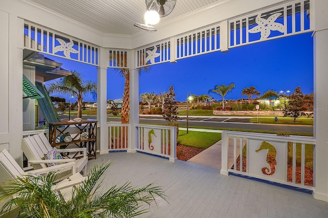 patio at twilight featuring a porch and a lawn