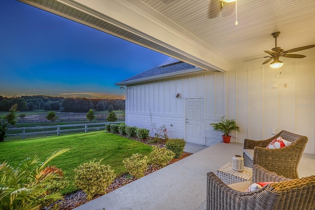 patio terrace at dusk featuring a lawn and ceiling fan