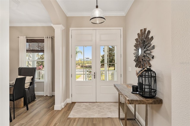 foyer entrance featuring crown molding, light hardwood / wood-style flooring, and ornate columns