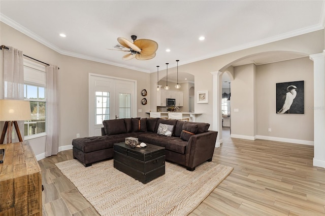 living room featuring crown molding, a wealth of natural light, light hardwood / wood-style flooring, and ceiling fan