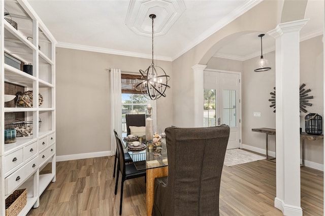 dining space featuring a notable chandelier, hardwood / wood-style flooring, crown molding, and ornate columns