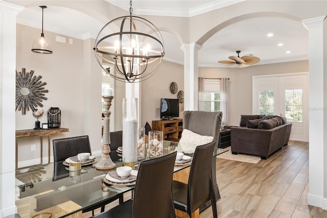 dining room with ceiling fan with notable chandelier, light wood-type flooring, ornamental molding, and ornate columns