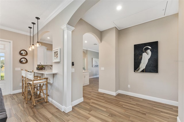 interior space featuring ornate columns, crown molding, and light hardwood / wood-style flooring