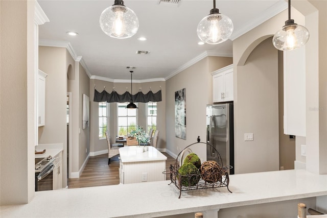 kitchen featuring crown molding, stainless steel appliances, kitchen peninsula, dark wood-type flooring, and pendant lighting