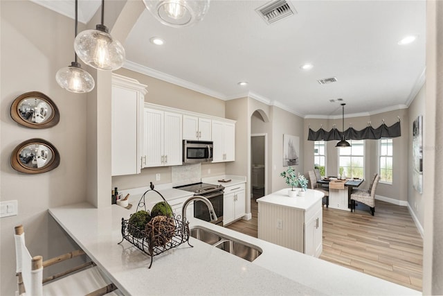 kitchen with light hardwood / wood-style flooring, appliances with stainless steel finishes, a center island, sink, and white cabinets